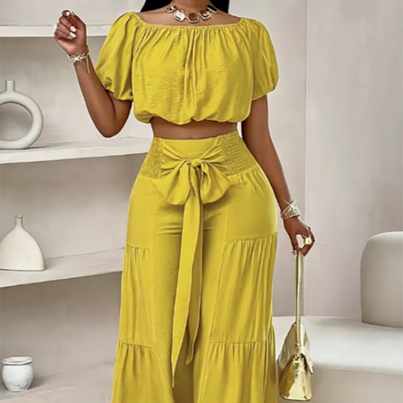 A woman wearing a two-piece set with an off-shoulder crop top and matching high-waisted flared pants with a tie detail.