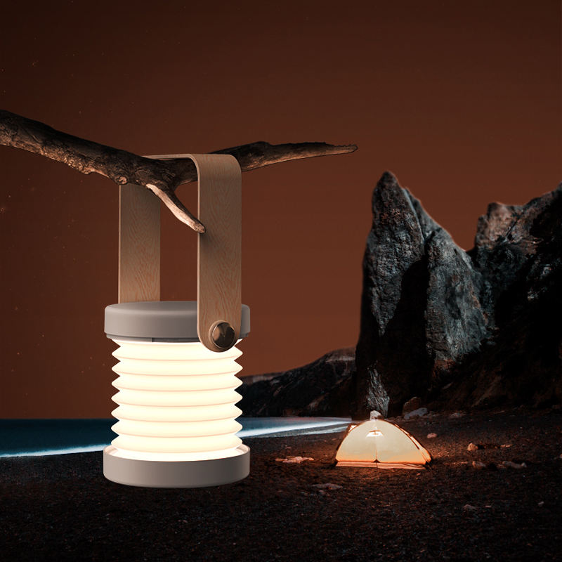Foldable minimalist LED lantern lamp in a neutral finish on a wooden surface.
