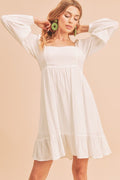 White mini dress with square neckline, dramatic balloon sleeves, and a tiered ruffled hem.