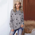 A woman wearing a loose-fitting gray long-sleeve hooded top with a black star print.