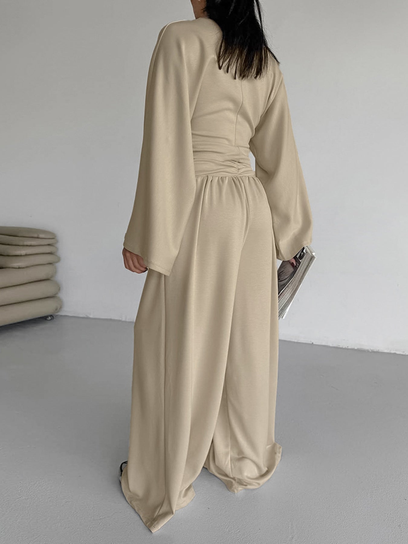 Person wearing a beige jumpsuit in a minimalistic room.
