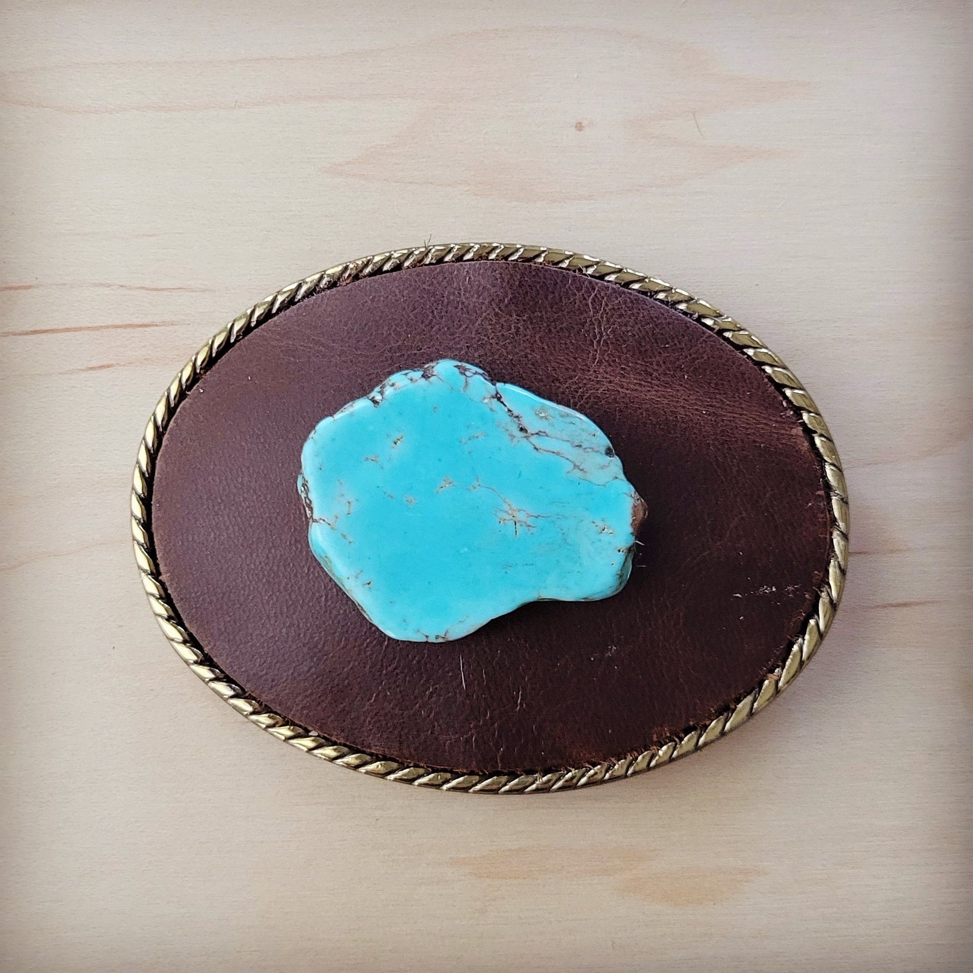 Rope edge brown leather belt buckle with a center blue turquoise stone