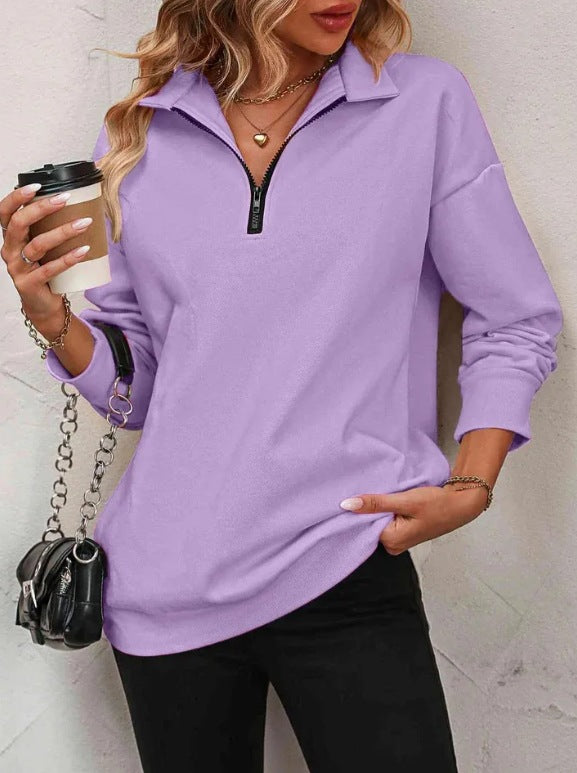 Woman wearing a purple long-sleeve top with a zipper, holding a coffee cup.