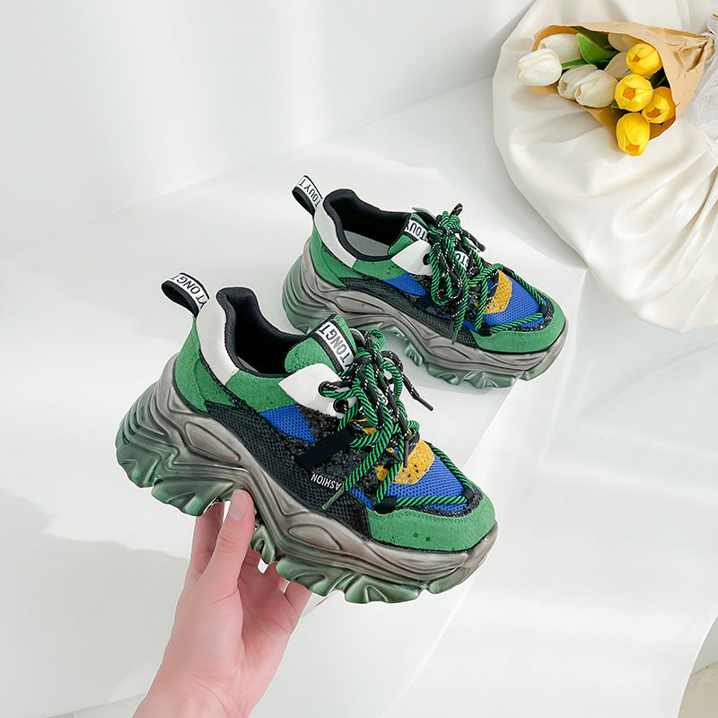 Two pairs of multicolor women's chunky sole sneakers, one green/blue/yellow, one red/yellow/brown, on a white background with a hand holding one shoe.