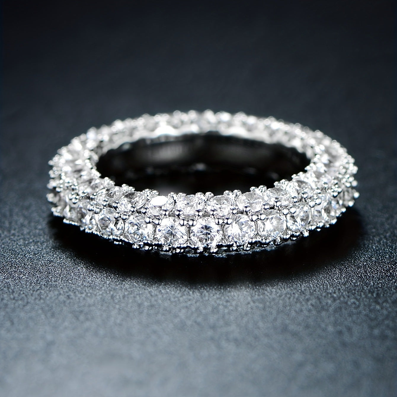 Minimalist three-stone cubic zirconia ring in polished silver finish on a neutral background