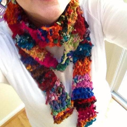 Finished 86-inch scarf knitted with colorful ribbon yarn, displayed on a wooden table.
