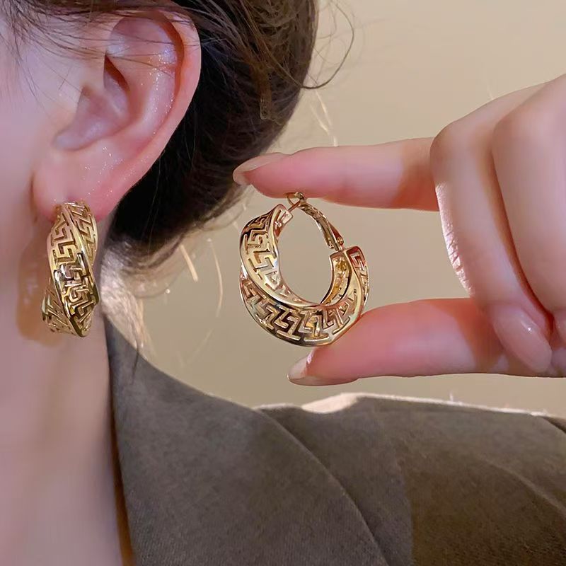 Close up of elegant silver needle twisted hollow hoop earrings in a European-American luxury style.