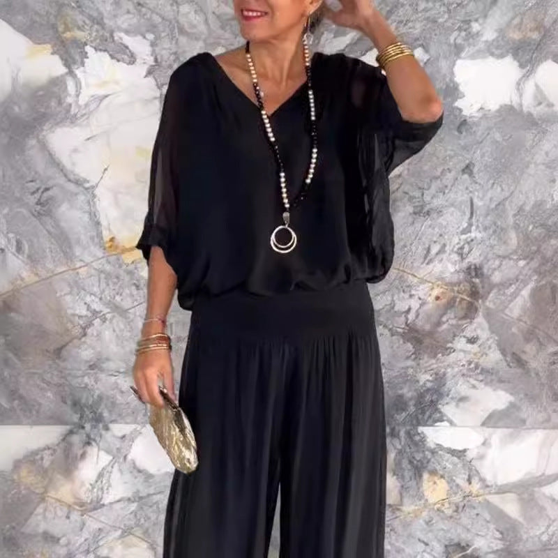 A woman wearing a matching solid color chiffon two-piece set with a loose V-neck top and wide-leg trousers.