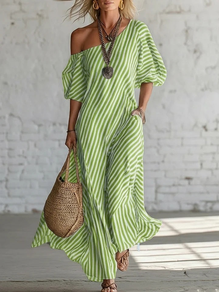 A woman wearing a striped one-shoulder midi dress with side pockets.