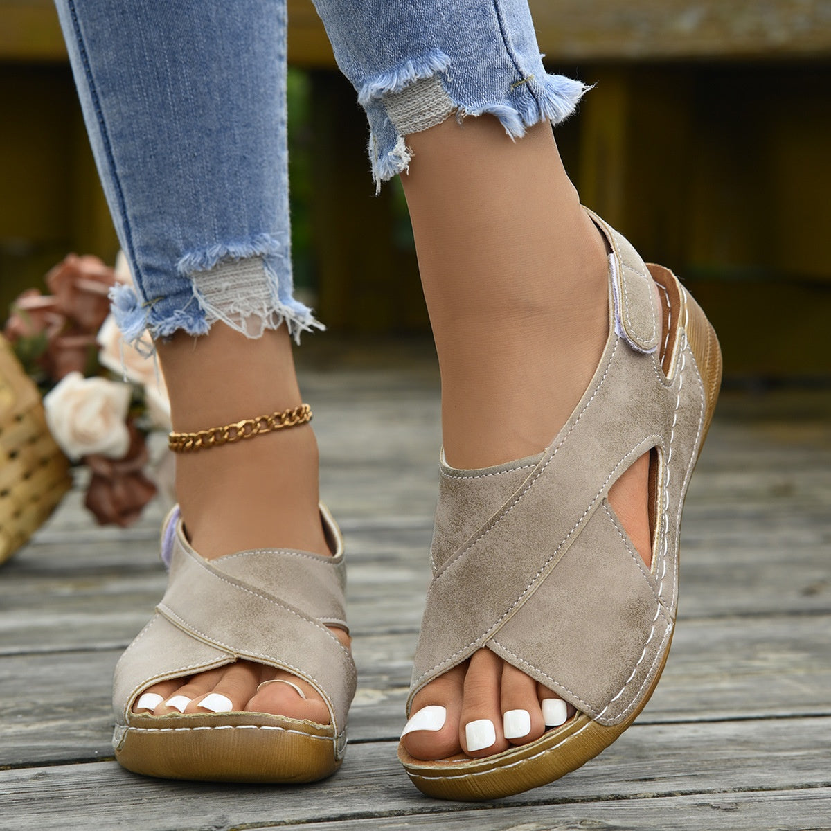 Women's platform Roman sandals in taupe and tan with Velcro closure worn in a casual beach setting.