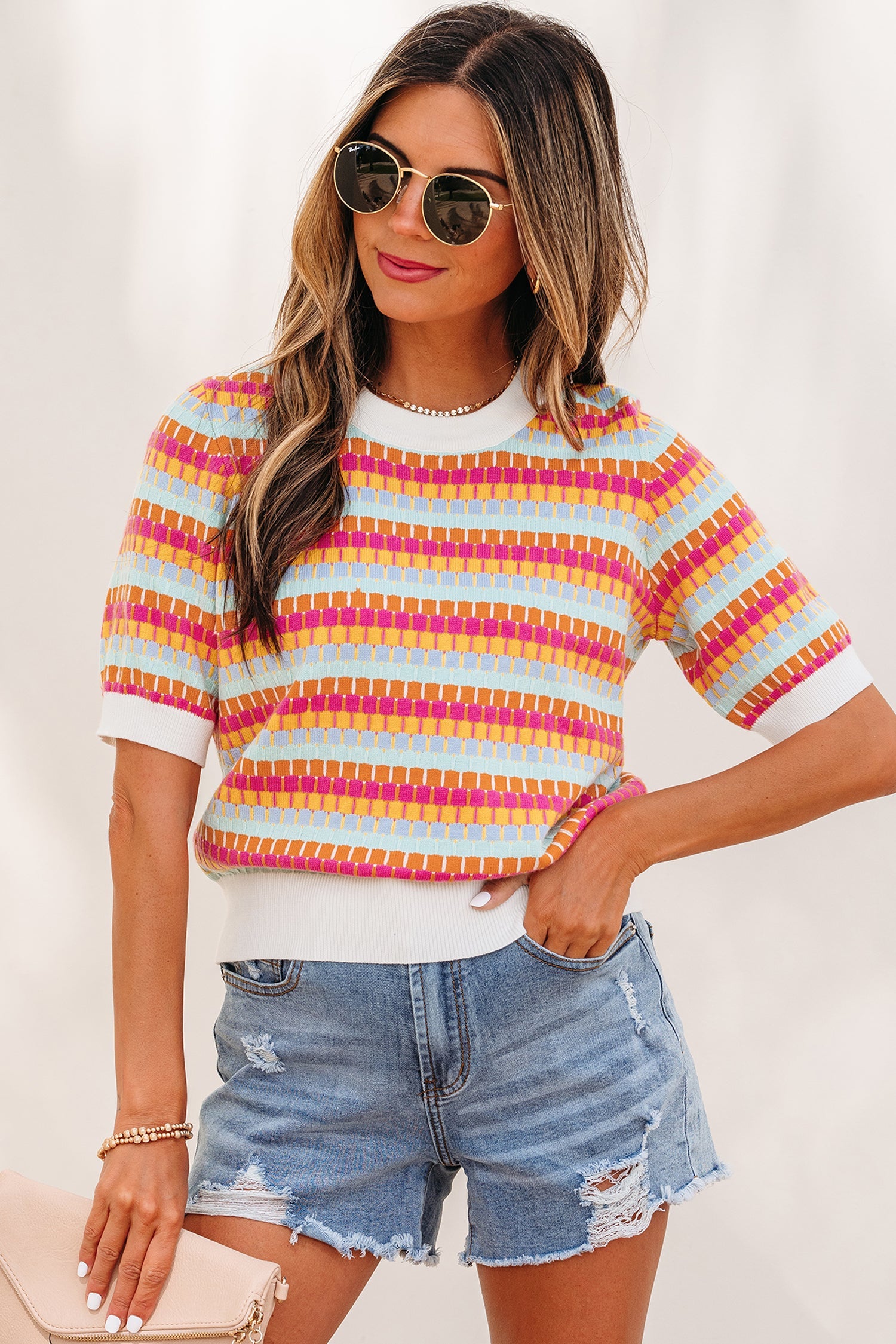 Women wearing Bellamy short sleeve knit sweater with abstract stripes in white, light-blue, orange, and fuchsia