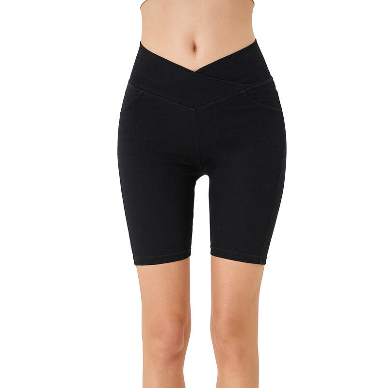 Woman wearing high-waisted fitted denim shorts in black, showing the stretch fabric and sporty minimalist cut.