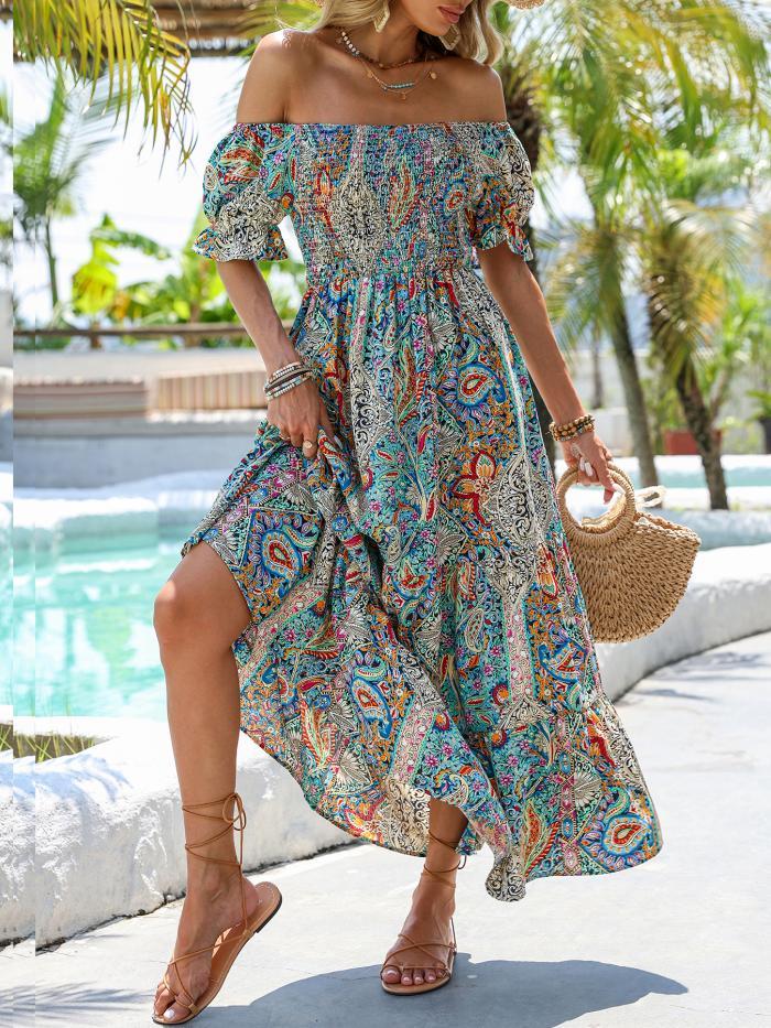 A woman wearing a vibrant multi-colored paisley off-shoulder maxi dress with a smocked bodice and puff sleeves, standing near a pool.