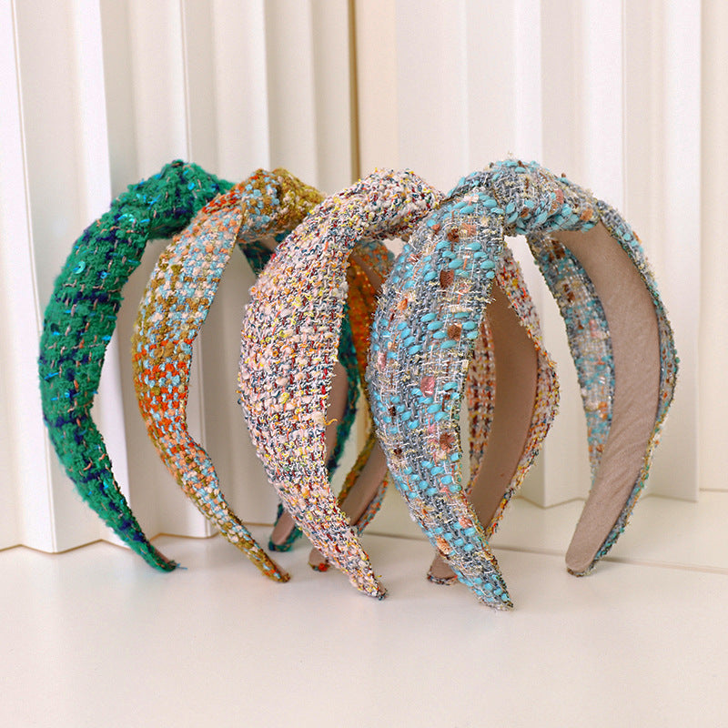 Collection of woolen tweed knot headbands in various multi-color patterns and a solid green, displayed on a white background.