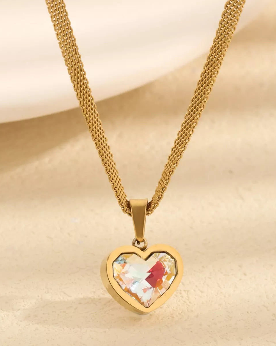 Gold heart-shaped pendant necklace with a colorful heart design on a beige background