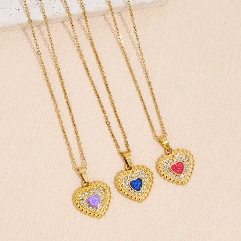 Heart-shaped stainless steel pendant necklace with inlaid rhinestones and drop-oil detailing on a white background.