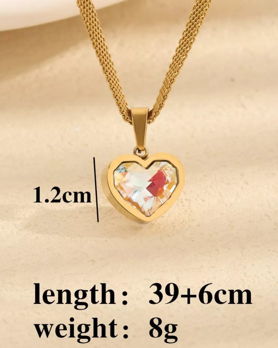Gold heart-shaped necklace with a colorful pendant on a beige background
