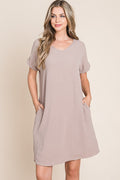 A minimalist taupe V-neck short sleeve dress with visible functional pockets.