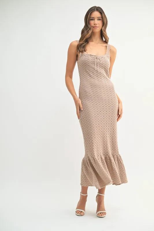 Woman wearing a sleeveless white crochet knit midi dress with a ruffled hem