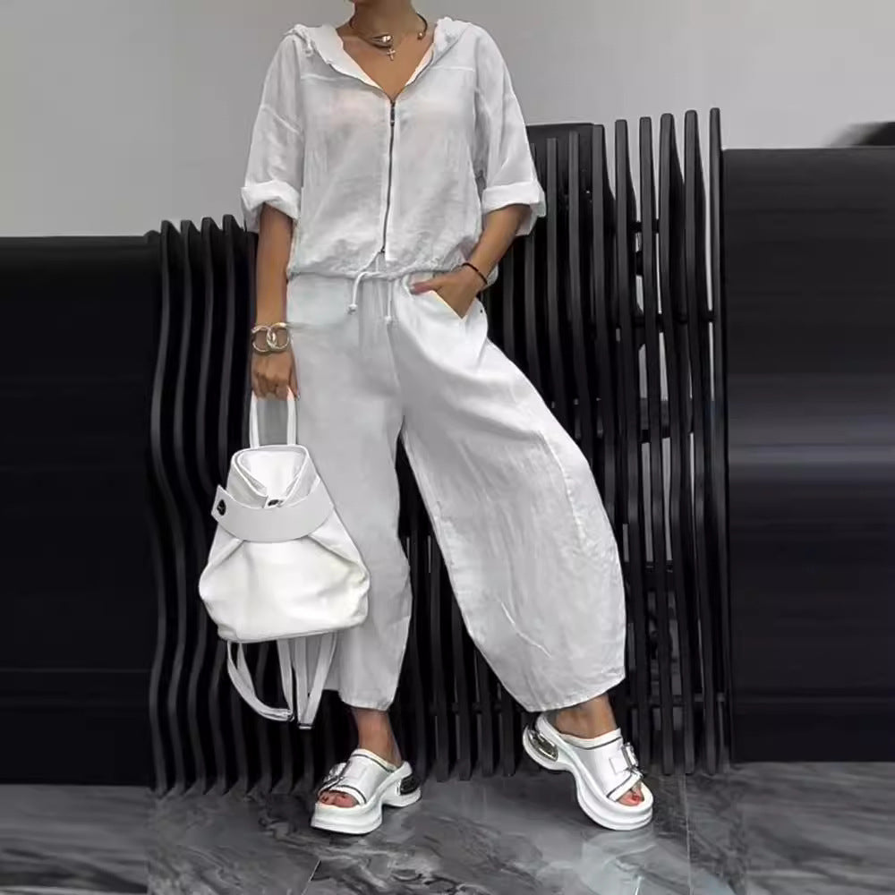 A woman wearing a white hooded cotton linen top and matching wide-leg pants set.
