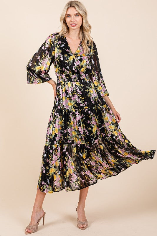 Woman wearing a romantic floral print satin midi dress with smocked bodice and tiered skirt.