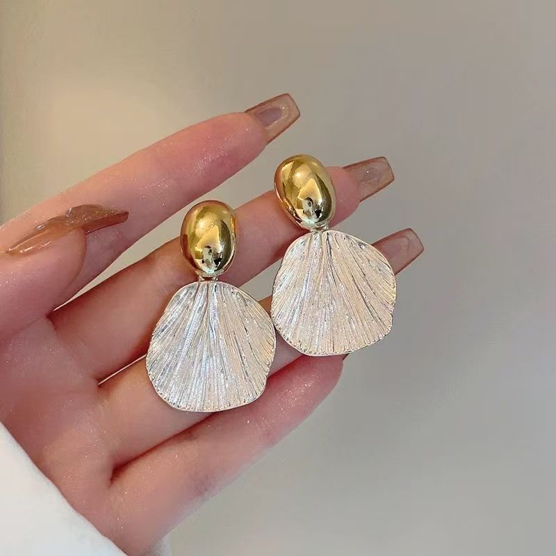 Close up of two-tone irregular shell texture statement earrings in gold and silver finish
