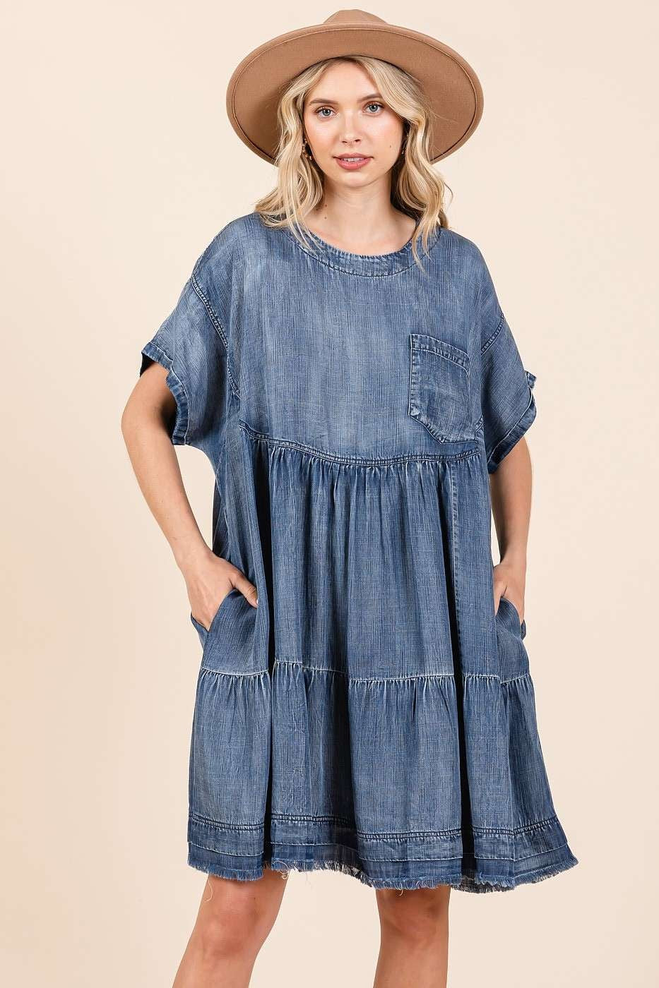 Model wearing a relaxed, oversized blue denim mini dress in a casual boho style