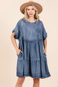 Model wearing a relaxed, oversized blue denim mini dress in a casual boho style