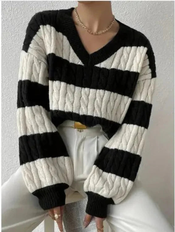 A person wearing a black and white striped cable knit sweater with a V-neckline.