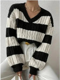 A person wearing a black and white striped cable knit sweater with a V-neckline.