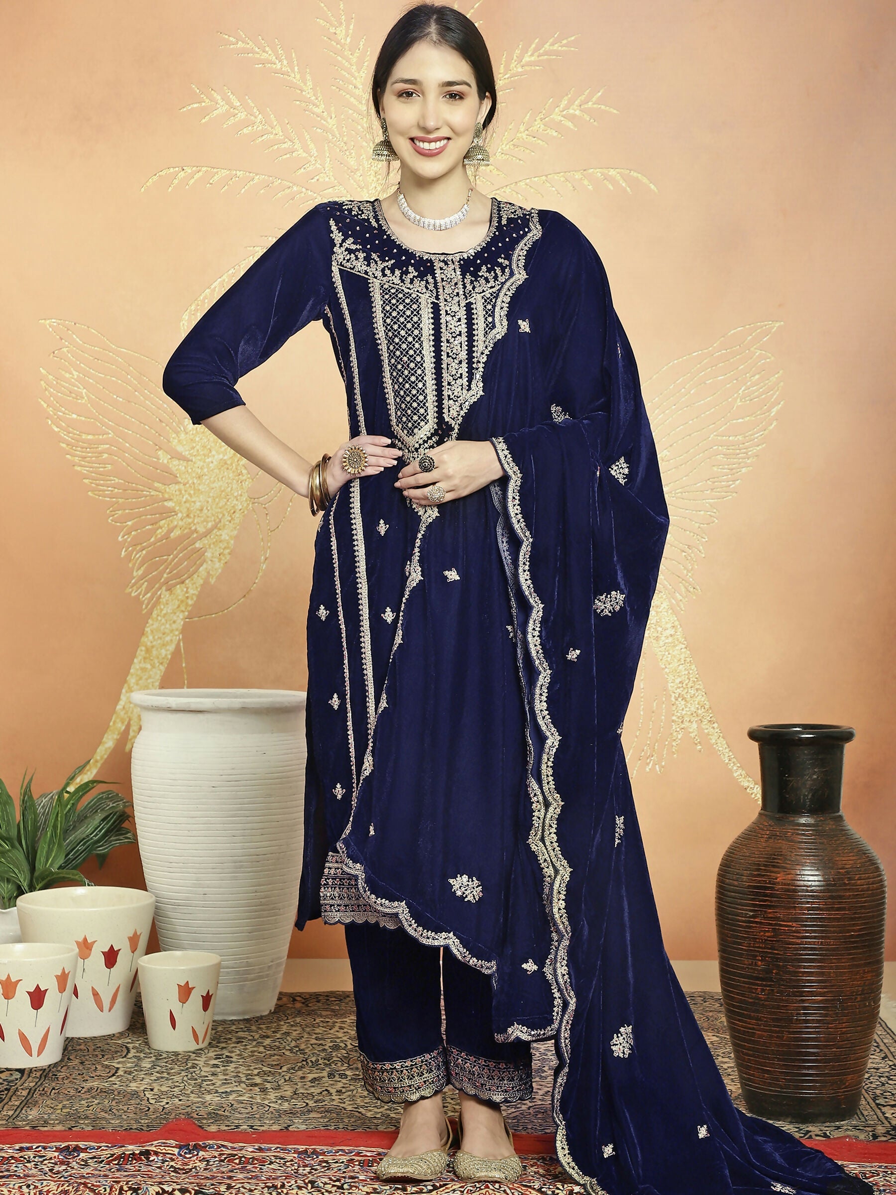 Woman wearing a Navy Blue velvet straight kurta with sequin and Resham thread embroidery and matching trousers.