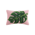 Close up of 12x20 inch palm leaf hook pillow with vibrant pink background and green botanical design on a sofa