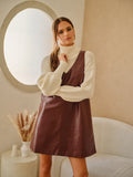 Model wearing a wine-colored faux leather shift dress layered over a cream turtleneck sweater