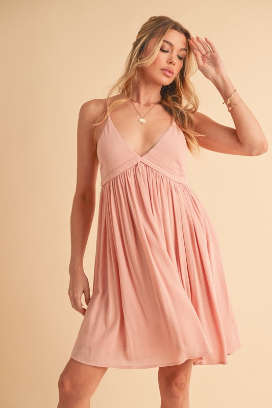 Dusty-rose colored mini cami dress with ruched detailing and a plunge neckline.
