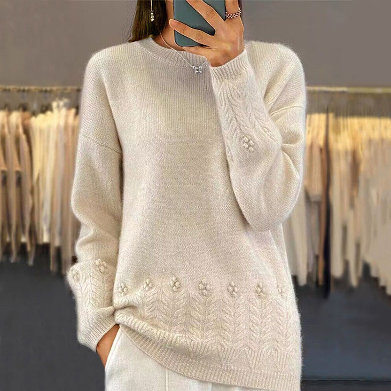Close up shot of a cream-colored women's sweater featuring delicate 3D floral embroidery along the hem and sleeve cuffs.
