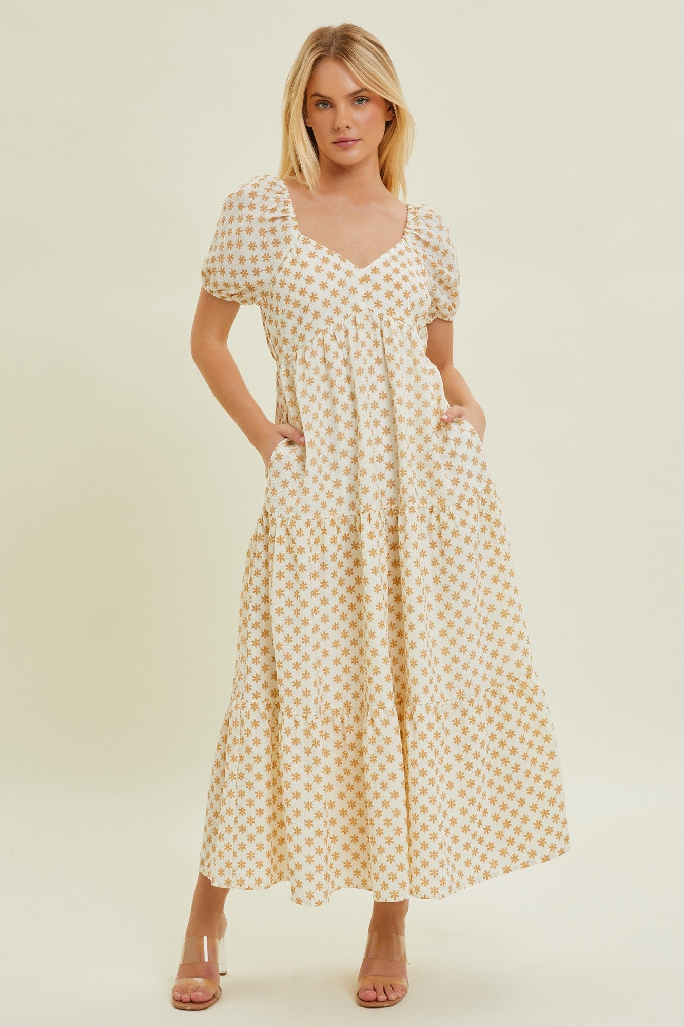 A woman wearing a yellow floral print tiered maxi dress with a sweetheart neckline and short puff sleeves.