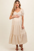 Woman wearing a yellow floral print maternity maxi dress with puff sleeves and a tiered skirt.