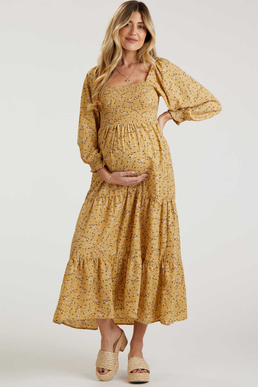 Woman wearing a yellow floral long sleeve smocked maternity maxi dress