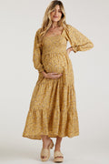 Woman wearing a yellow floral long sleeve smocked maternity maxi dress