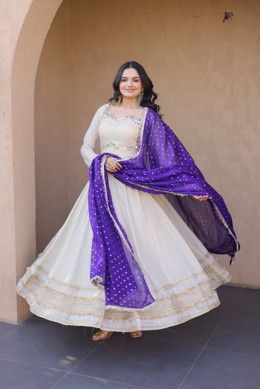 A cream-colored Cosmos gown with intricate Zari embroidery and real mirror work, paired with a matching dupatta.