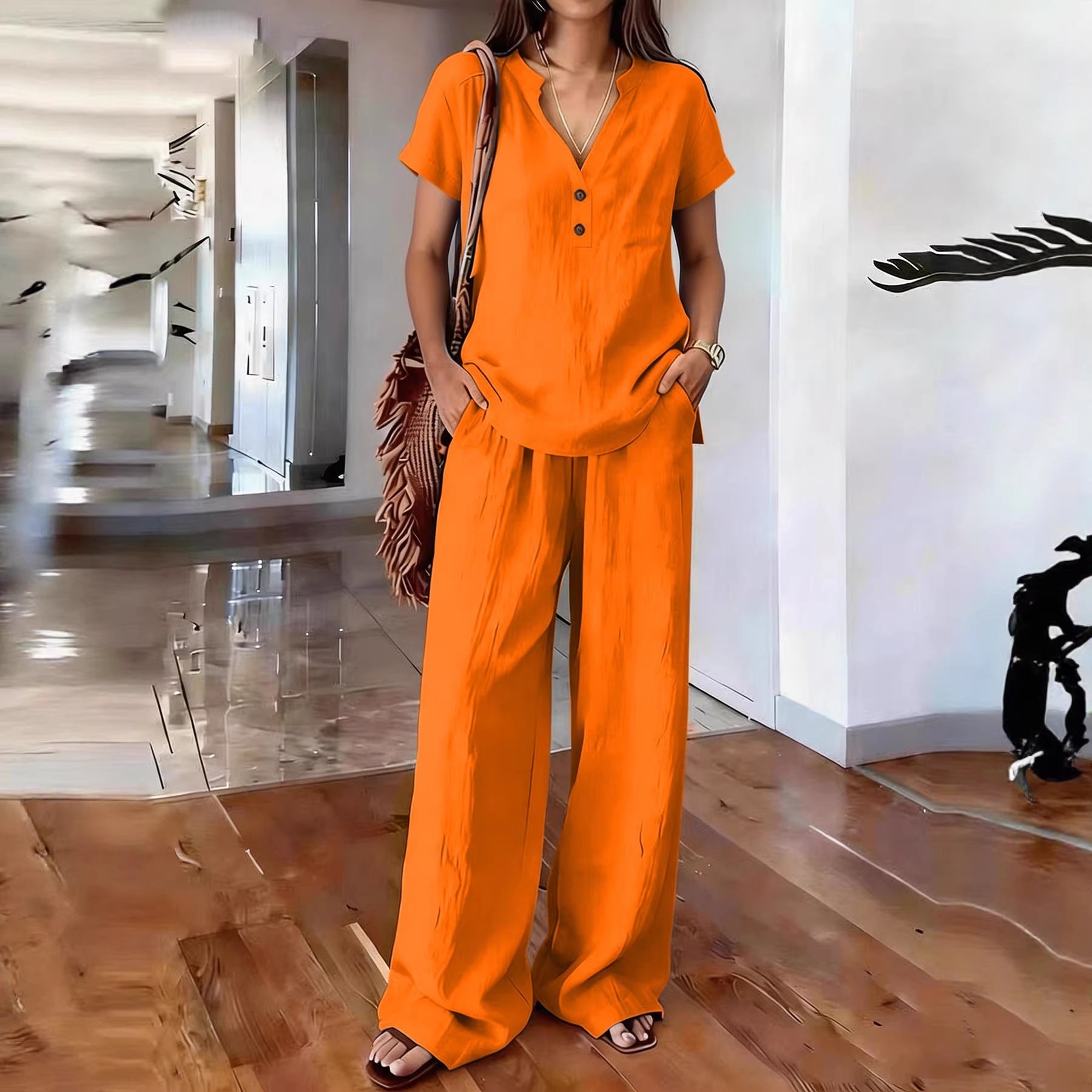 A model wearing a casual solid color two-piece matching set with a button-front short sleeve top and wide-leg trousers.