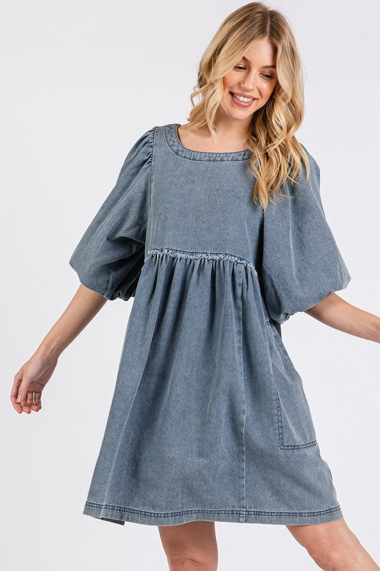 Woman wearing a vintage-inspired washed denim dress with puff sleeves and round neckline