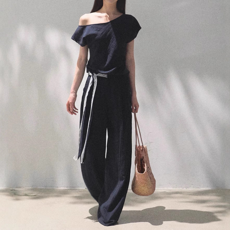 Model wearing a navy blue off-shoulder linen-blend top and wide-leg trousers with lace waist detail.
