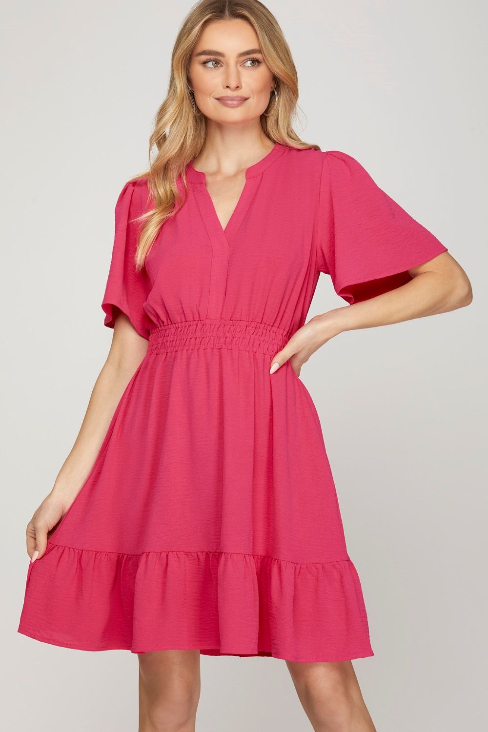 Woman wearing a feminine mini dress with ruffled hem and flutter sleeves