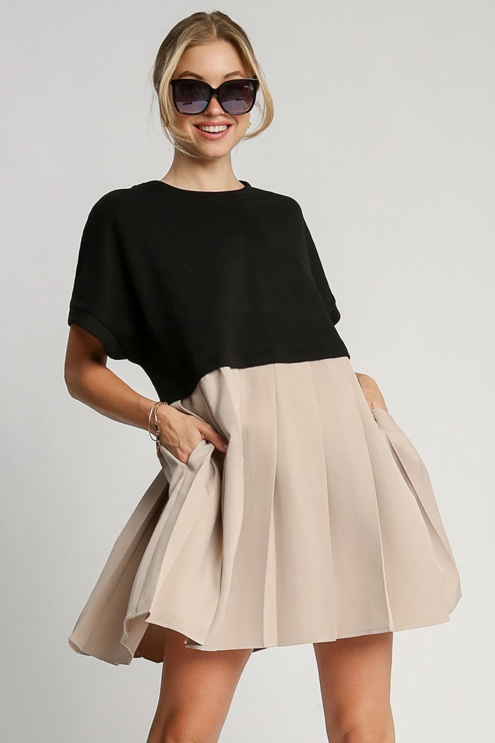 Black minimalist round neck dress with ruched detailing and functional side pockets.