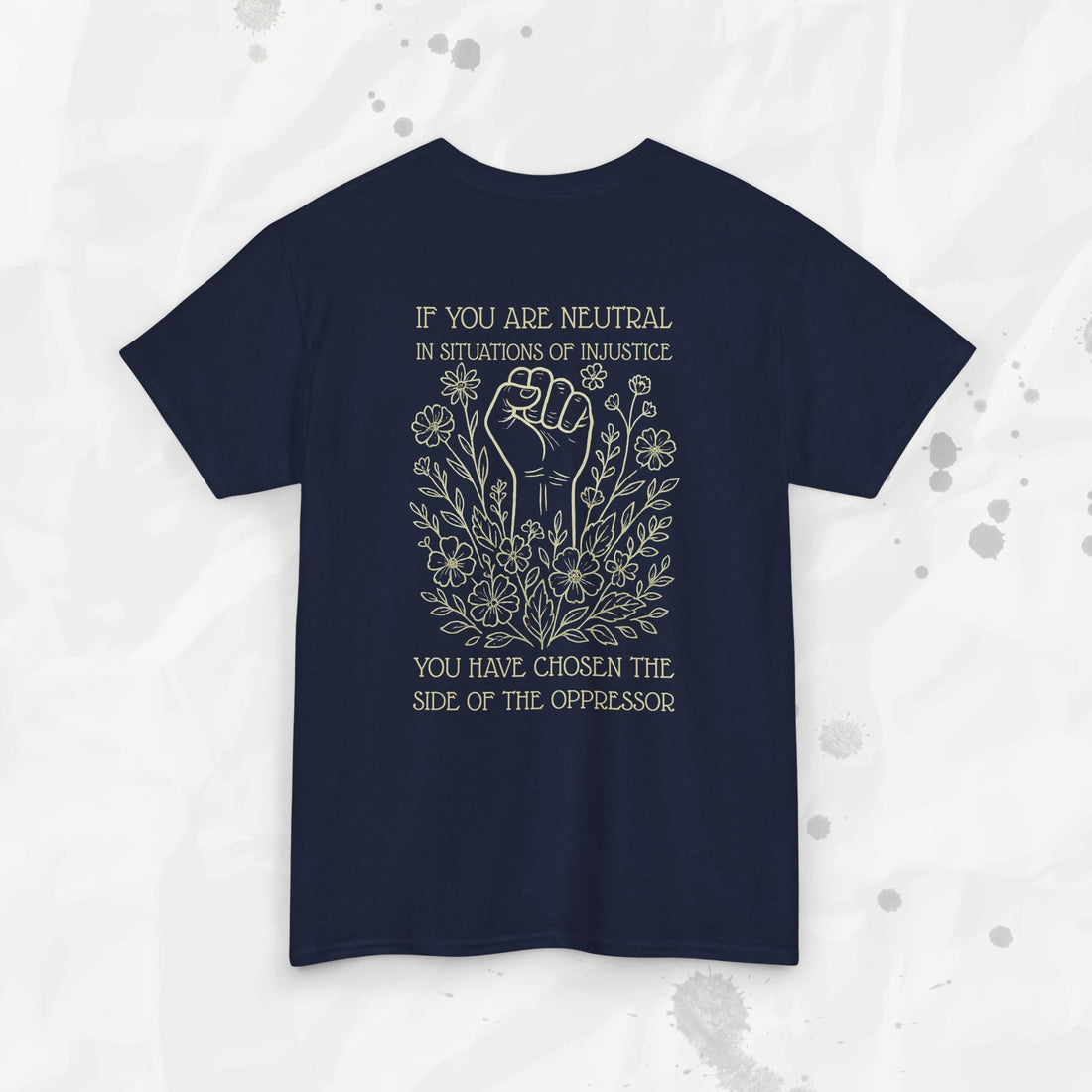 A back view of a graphic t-shirt featuring a raised fist surrounded by botanical illustrations and the text: If you are neutral in situations of injustice, you have chosen the side of the oppressor.