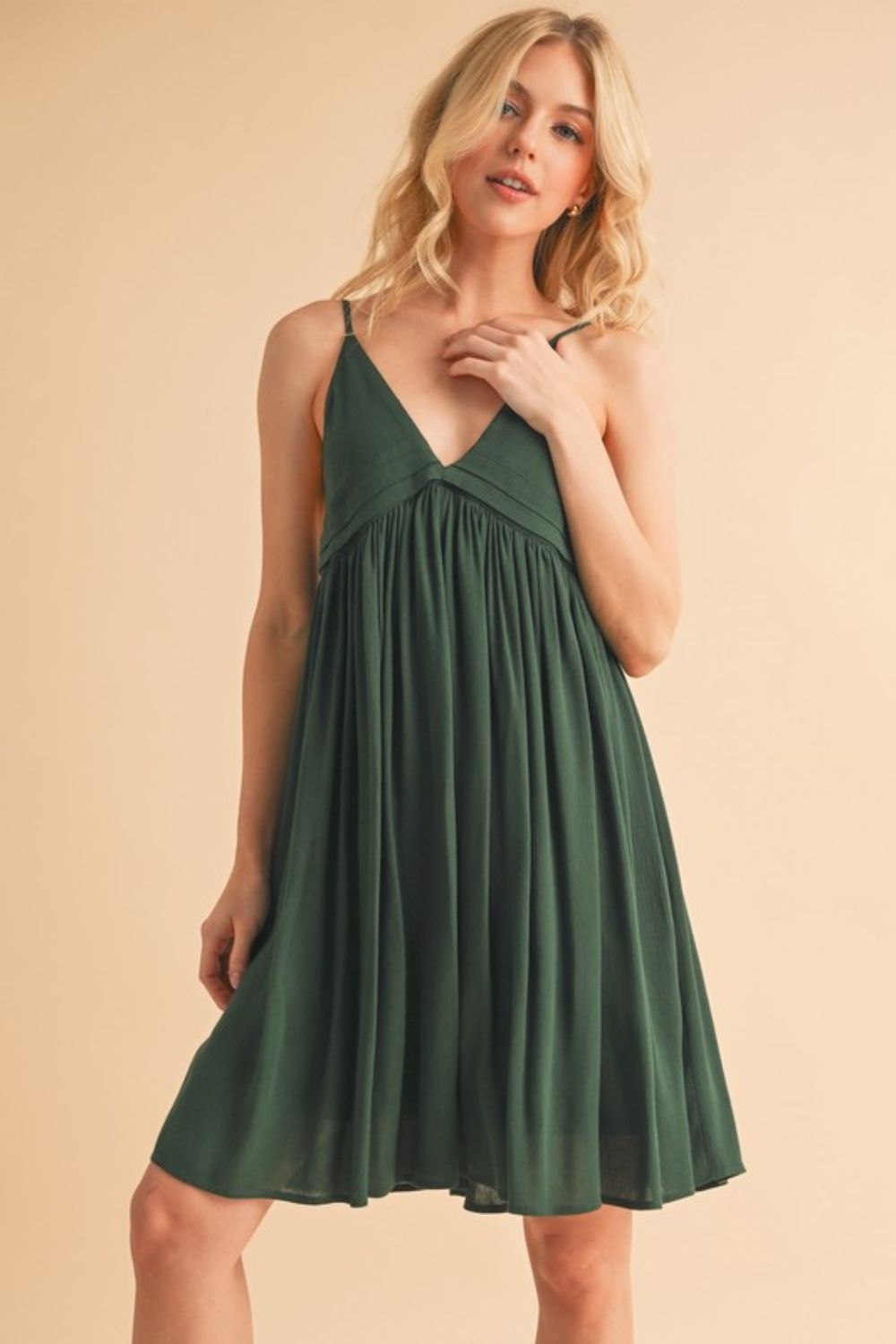 Woman wearing a flattering ruched mini cami dress with a plunge neckline for a night out