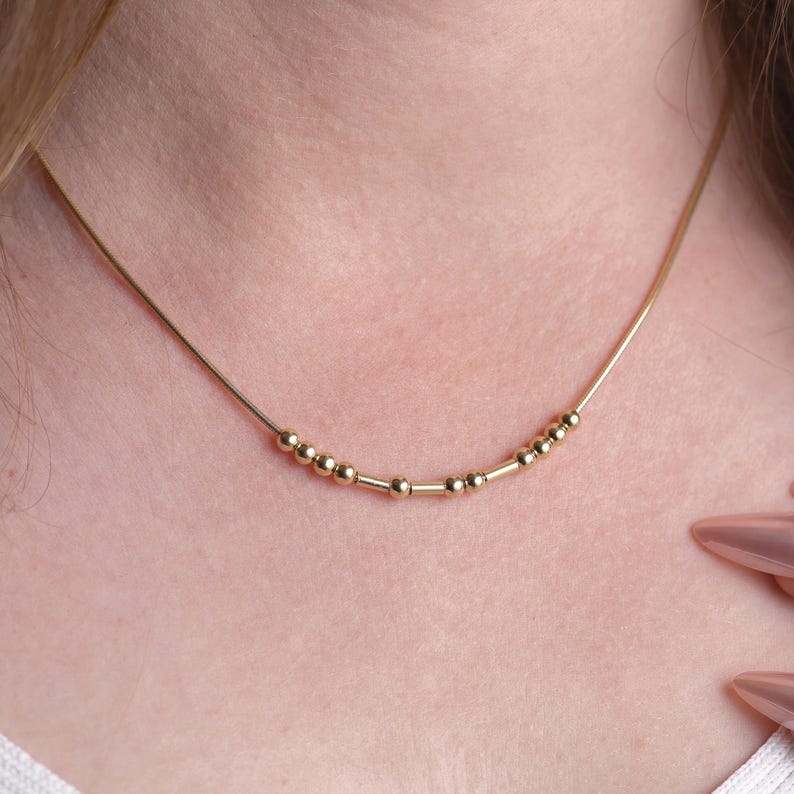 Customized Morse Code name necklace with elegant bead and tube details on a simple chain.