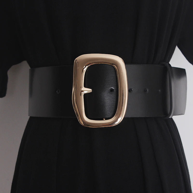 Wide black cowhide waist belt with large gold buckle worn over a black outfit