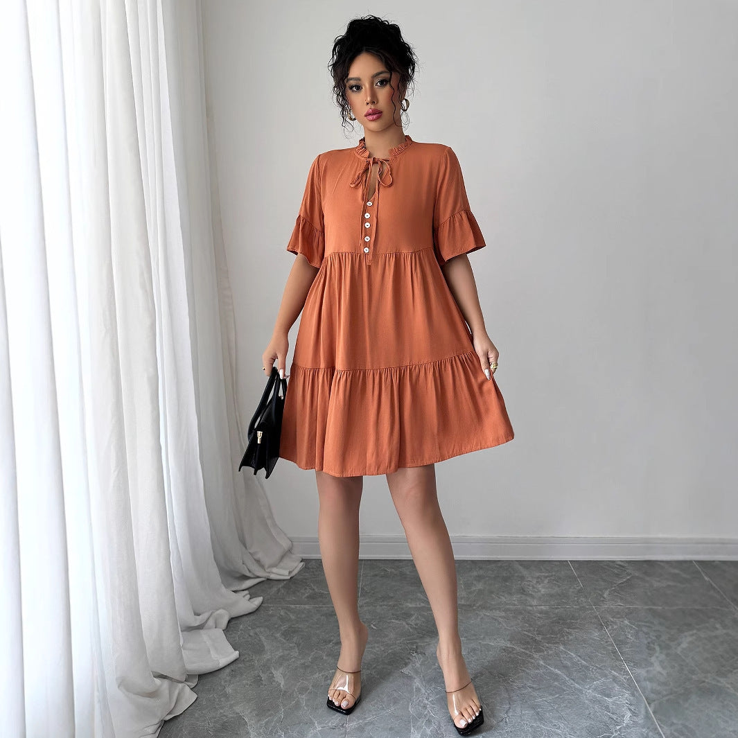 Woman wearing a rust orange A-line mini dress with ruffle sleeves and lace-up detailing